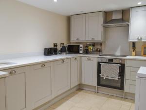 a white kitchen with white cabinets and appliances at The Granary in Little Chart