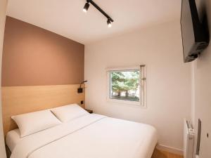 a bedroom with a white bed and a window at Kyriad ECO - Tours Nord in Tours