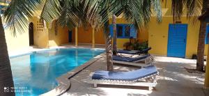 ein Schwimmbecken mit zwei Stühlen und einer Palme in der Unterkunft Laduno in M'bour
