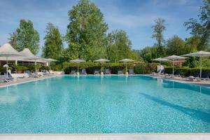 a large swimming pool with chairs and umbrellas at UNA Hotels Forte Dei Marmi in Forte dei Marmi