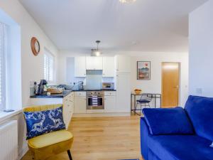 a living room with a blue couch and a kitchen at Vineyard's Apartment - Uk36748 in Ely