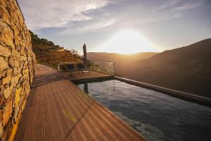 a swimming pool on a wooden deck with the sun setting at Quinta Vale de Lobos in Folgosa