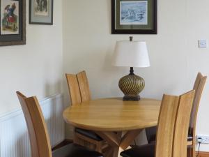 a wooden table with chairs and a lamp on top at Cloud Cottage in Duns