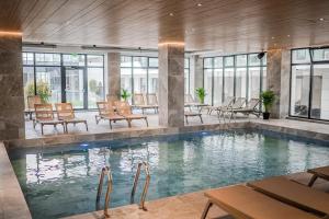 a swimming pool with chairs and tables in a building at Zyra Blue Heart Pool & Spa in Năvodari