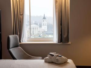 a room with a bed and a chair and a window at Novotel Vilnius Centre in Vilnius +99 photos