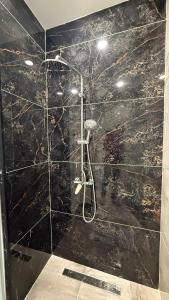 a bathroom with a shower with black marble walls at إقامة الرمال الذهبية in Les Hamiane