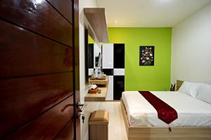 a bedroom with a bed and a green wall at D'Pande Kuta in Kuta