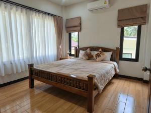 a bedroom with a large bed in a room with windows at Thara Bohemia Villa in Hinkong