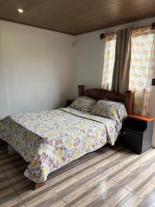 a bedroom with a bed with a quilt on it at Cabañas Casa Tucano in San Ramón