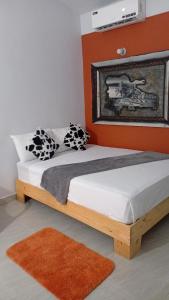 a bed in a bedroom with an orange wall at Hogar flores in La Ceiba