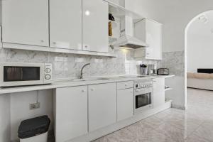 a white kitchen with white cabinets and appliances at Villa Gabriela in Tarajalejo