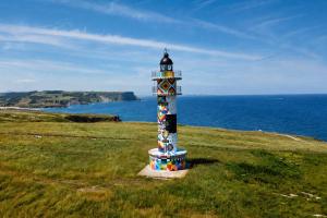 a lighthouse in the middle of a field near the ocean at Kampaoh Somo Playa in Somo