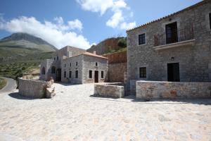 un grande edificio in pietra con una montagna sullo sfondo di Vasilios Apartments Hotel a Limeni