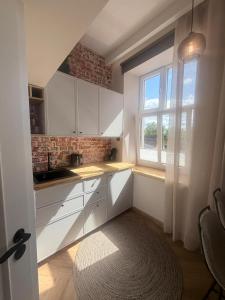 a kitchen with white cabinets and a window and a rug at Keskväljaku Studio apartment in Võru