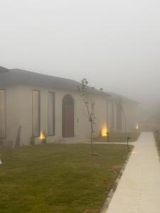 a house on a foggy day with a grass yard at Al Badr Villas Resort in Sawdāʼ +14 photos
