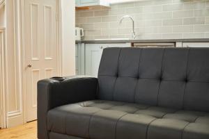 a black couch sitting in a kitchen with a sink at Host & Stay - The Spinney in Consett