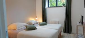 two white beds in a room with a window at L'Etable d'Armand in Névez