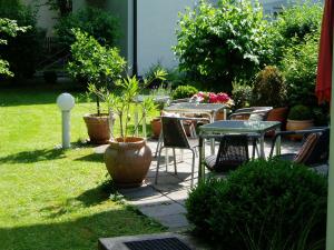 eine Terrasse mit Tischen, Stühlen und Topfpflanzen in der Unterkunft Villa am Schlosspark in München