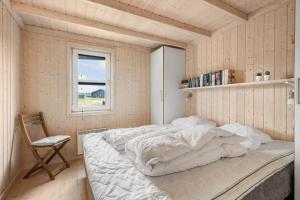 a bedroom with a bed and a chair and a window at LN602-Hjorring-Harerenden-71 in Hjørring