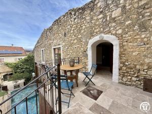a stone building with a table and chairs on a balcony at Le gîte du clos in Roquefort-des-Corbières