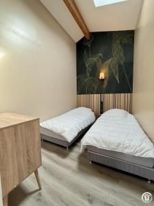 a bedroom with two beds and a painting on the wall at Le gîte du clos in Roquefort-des-Corbières +7 photos