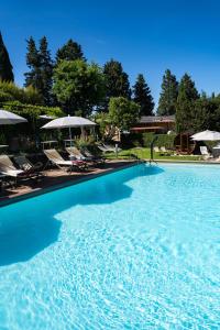 a large swimming pool with chairs and umbrellas at Villa Santa Chiara in Siena
