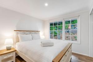 a white bedroom with a large bed and a window at North Avoca Coastal Escape in North Avoca