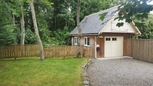 a garage with a fence and a wooden building at Loch Ness Studio Blairbeg in Drumnadrochit