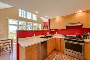 a kitchen with wooden cabinets and a red wall at Waterfront Bellingham Bliss: Steps to Beach! in Bellingham