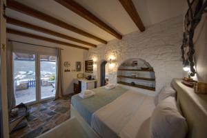 a bedroom with a large bed with a stone wall at EMERALD Villa in Kithnos