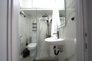 a white bathroom with a sink and a toilet at Paralia Sea View Suites in Paralia Katerinis