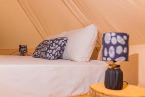 a bed with pillows and a lamp on a table at Barreo Nova Eco Resort in Abrafo