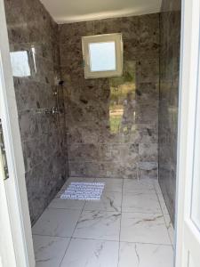 a bathroom with a shower with a stone wall at Bungalow-Guest House Alpina in Vusanje +37 photos