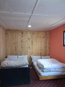 two beds in a room with wooden walls at Hotel sangam kalinchok kuri in Dolakhā