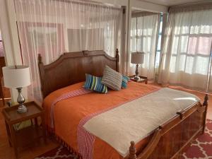 a bedroom with a bed with two lamps and windows at Casa Zuniga Extended Stay in Guanajuato +12 photos