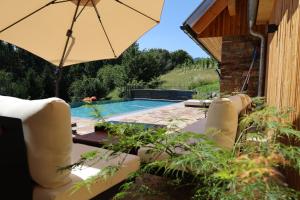 a patio with an umbrella and a swimming pool at Der Distelfalter in Oberhaag