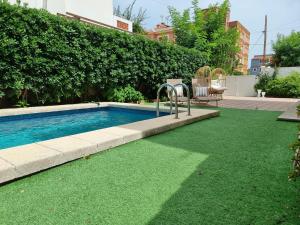 a swimming pool with green grass in a yard at MD Villa con piscina en Mareny Beach in Mareny Blau