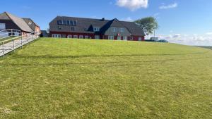 a house on top of a grassy hill at HaRE Ferienwohnungen een in Langeneß