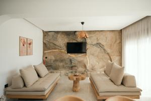 a living room with two couches and a stone wall at Villas Pasha in Faliraki