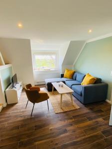 a living room with a blue couch and a table at HaRE Ferienwohnung DREE in Langeneß
