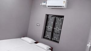 a white room with a bed and a window at Hotel Sabareesh Kanyakumari in Golden Rock