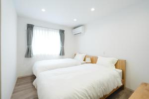 two beds in a white room with a window at Crescout Toa 1 in Gotemba