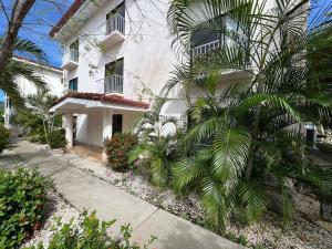 a white building with a palm tree next to a sidewalk at Tropical Stay in Coco in Coco