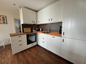 a kitchen with white cabinets and a sink at HaRE Ferienwohnungen Käptn Magda in Langeneß