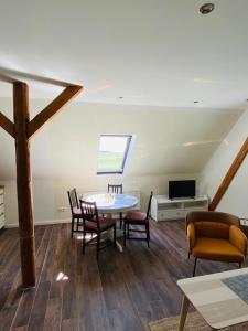 a living room with a table and chairs and a tv at HaRE Ferienwohnungen VEER in Langeneß