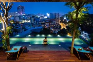a woman sitting on the edge of a swimming pool at night at Silverland Yen Hotel in Ho Chi Minh City