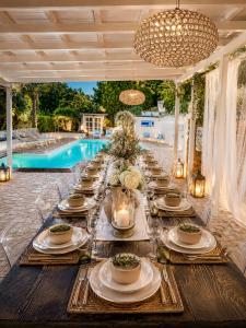 a long table set for a meal in front of a pool at Villa Silvio Relais in Civitanova Alta