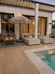 a patio with couches and an umbrella next to a pool at Superbe Villa très proche cannes in Mougins