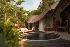 a swimming pool in the middle of a garden at Kaymana in Uluwatu