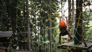 a young girl is swinging on a climbing net at Otta Apartments Golte in Mozirje